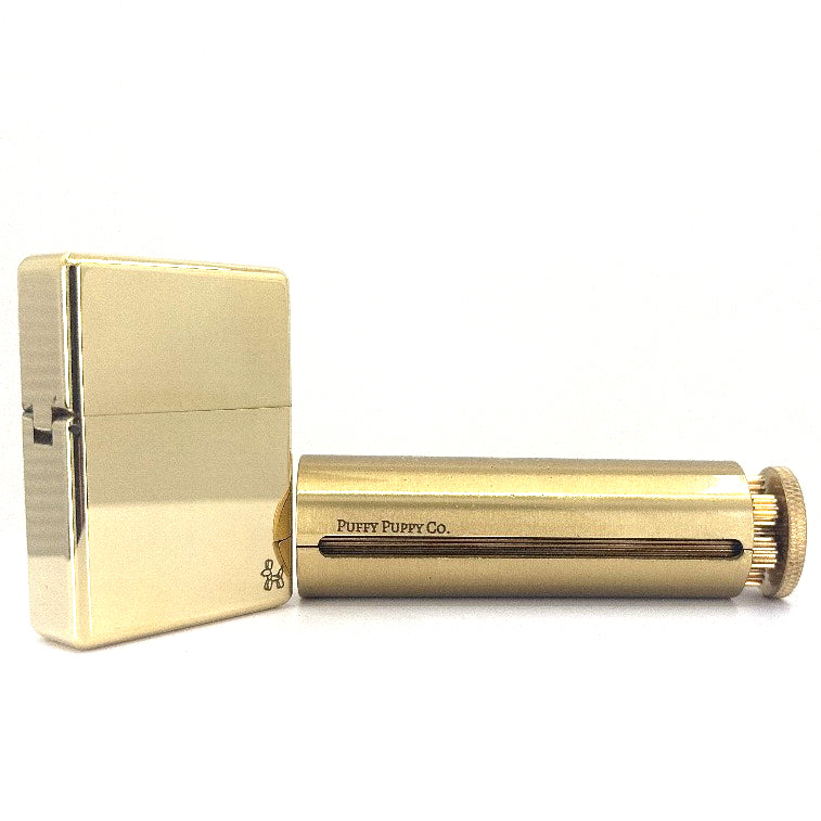 A vintage brass rolling machine and brass lighter.