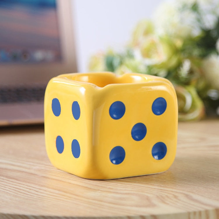 Yellow dice ashtray with blue dots on the table.