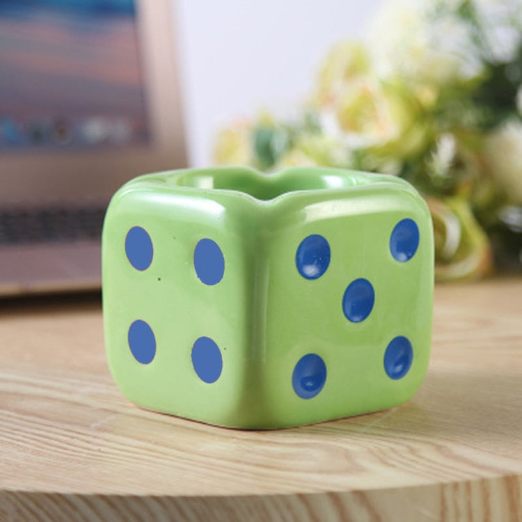 Green dice ashtray with blue dots on the table.