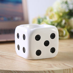 White dice ashtray with black dots on the table.