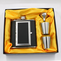 A black stainless steel whiskey flask with a cigarette compartment and two stainless steel shot glasses.