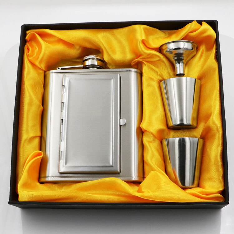 A silver whiskey flask with a cigarette compartment and two stainless steel shot glasses.